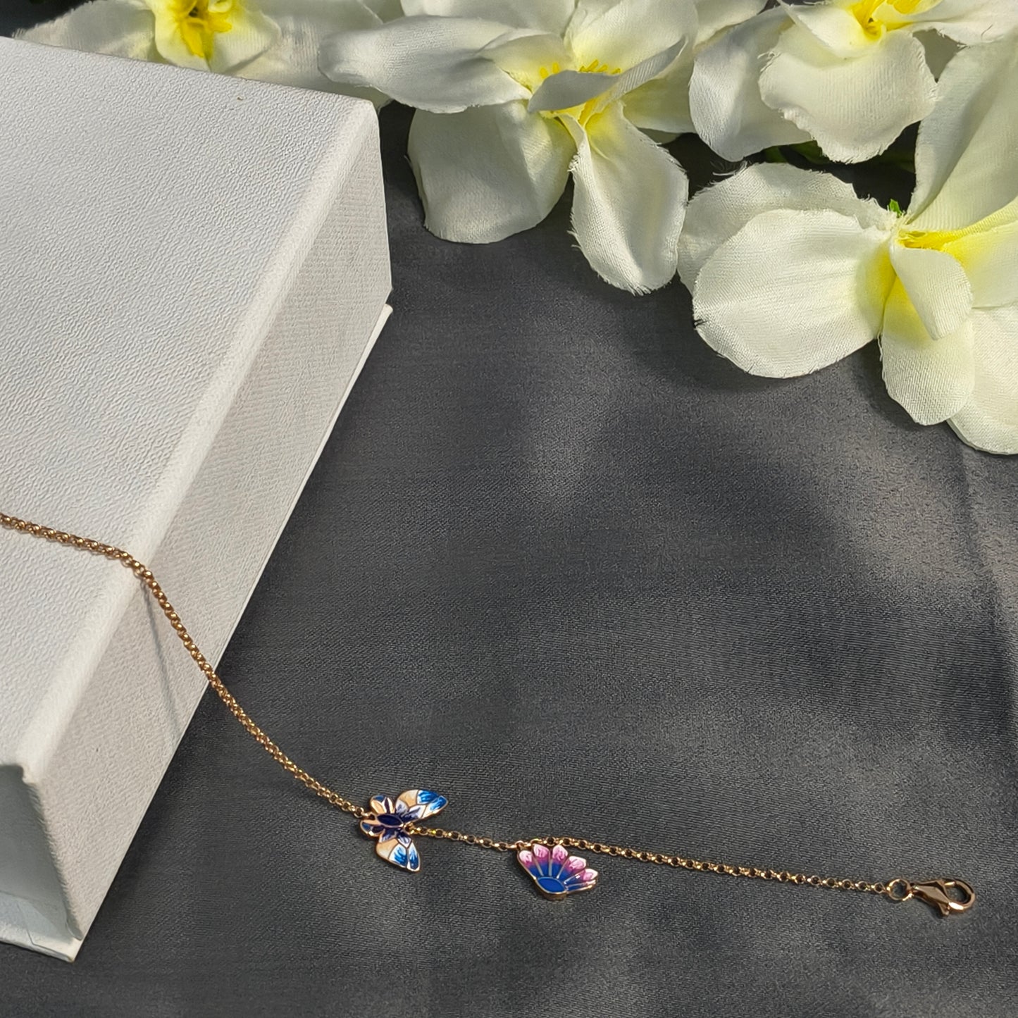 Butterfly-themed bracelet on a gray surface with white flowers