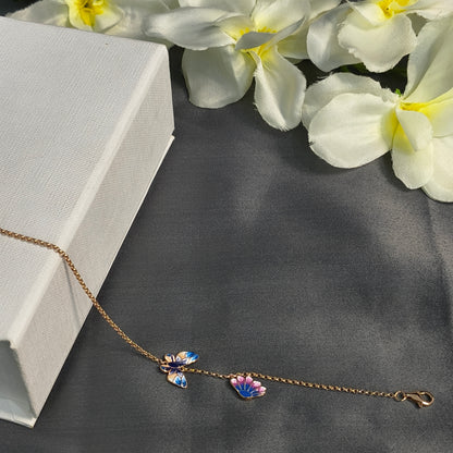 Butterfly-themed bracelet on a gray surface with white flowers