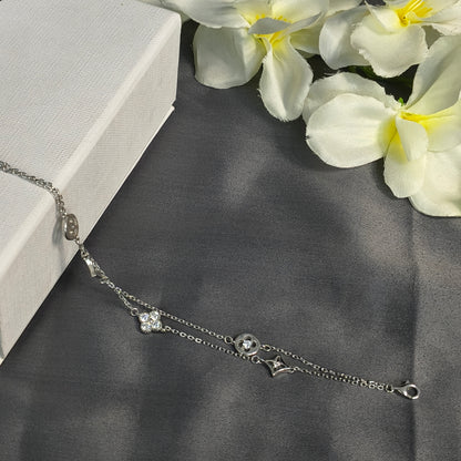 Silver bracelet with floral design on a dark fabric background with white flowers.