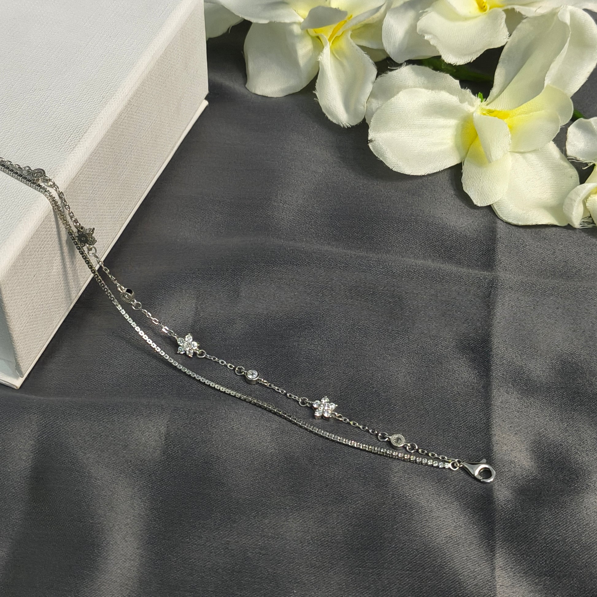 Silver bracelet with floral designs on a dark fabric background