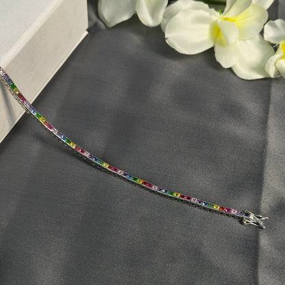 Multicolored gemstone bracelet on a dark fabric background with white flowers.