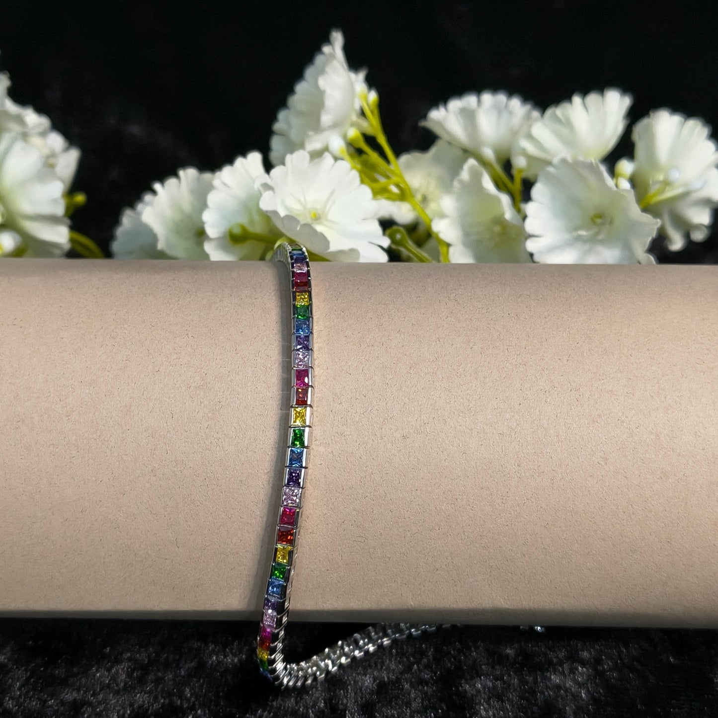 Multicolored gemstone bracelet on a wrist with white flowers in the background