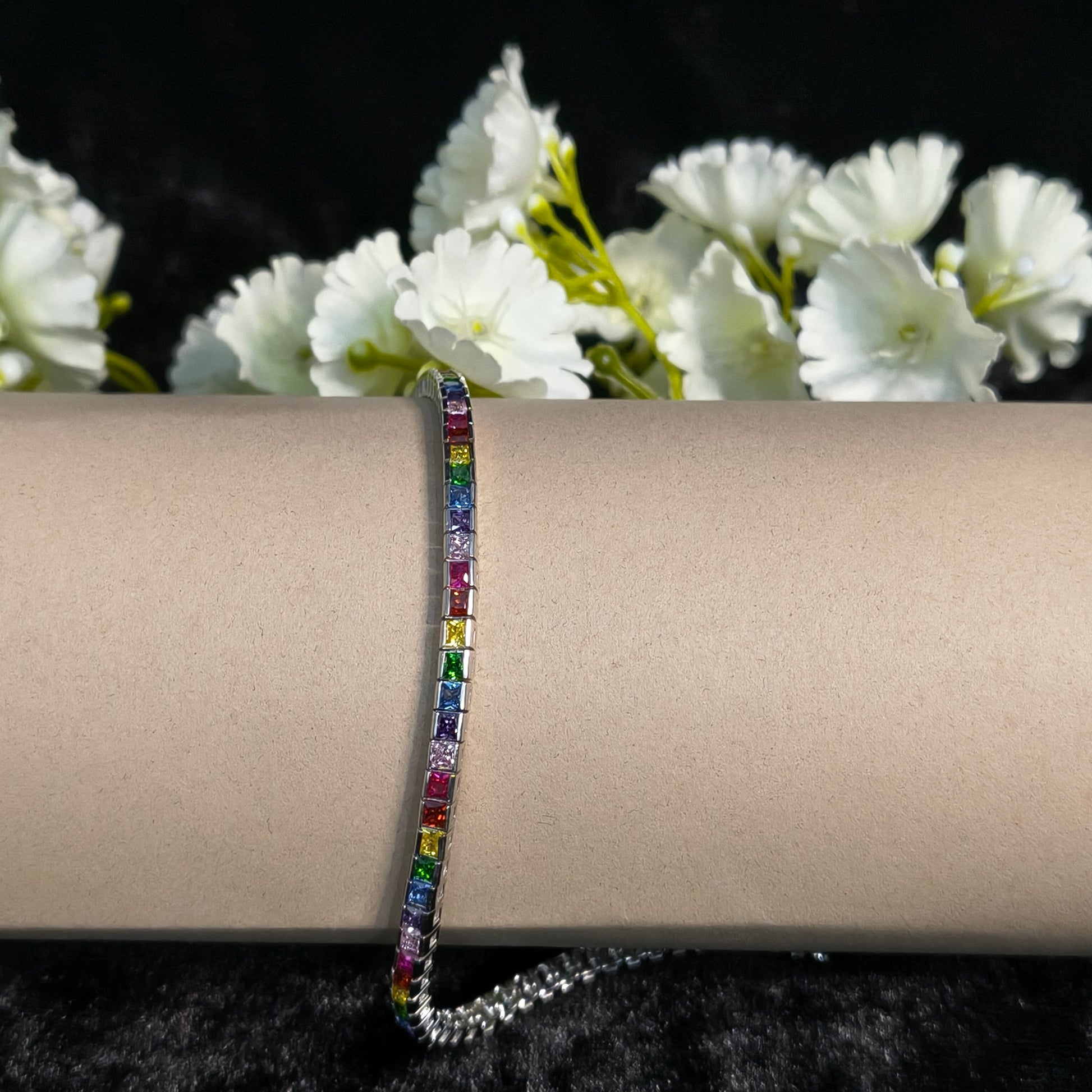Multicolored gemstone bracelet on a wrist with white flowers in the background