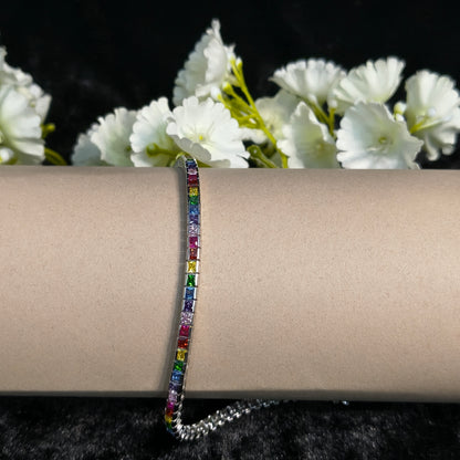 Multicolored gemstone bracelet on a wrist with white flowers in the background
