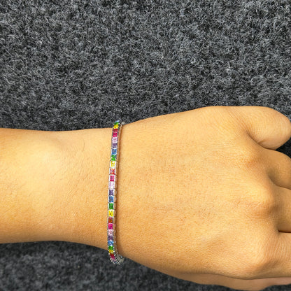 Multicolored beaded bracelet on a wrist against a gray background