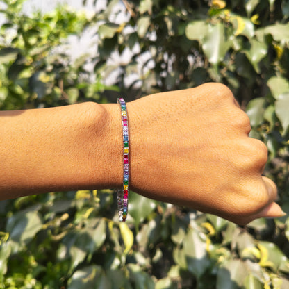 Hand wearing a colorful beaded bracelet with a green leafy background