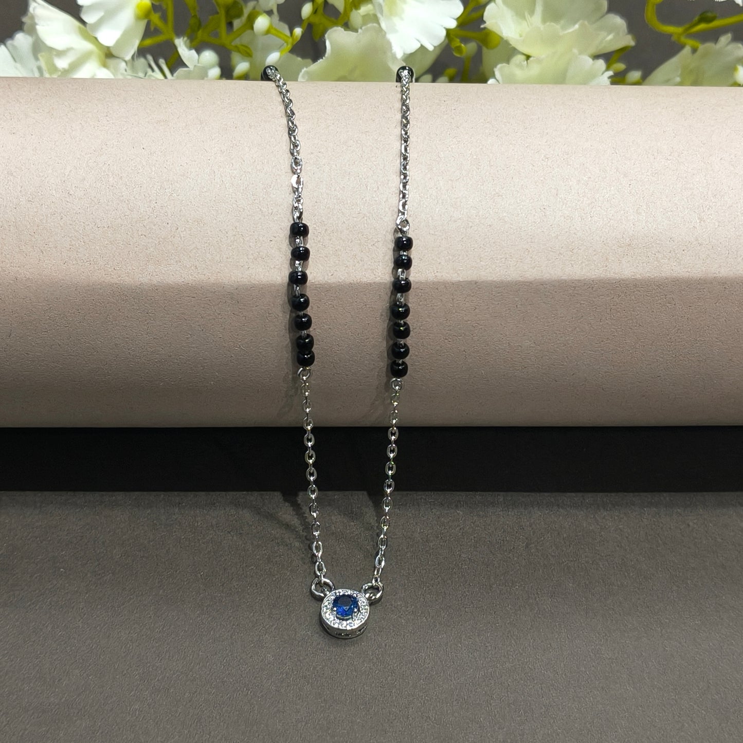 Bracelet with black beads and a blue gemstone on a gray background