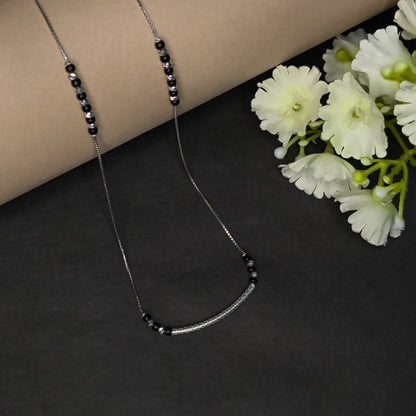 Necklace with black beads on a dark surface with white flowers
