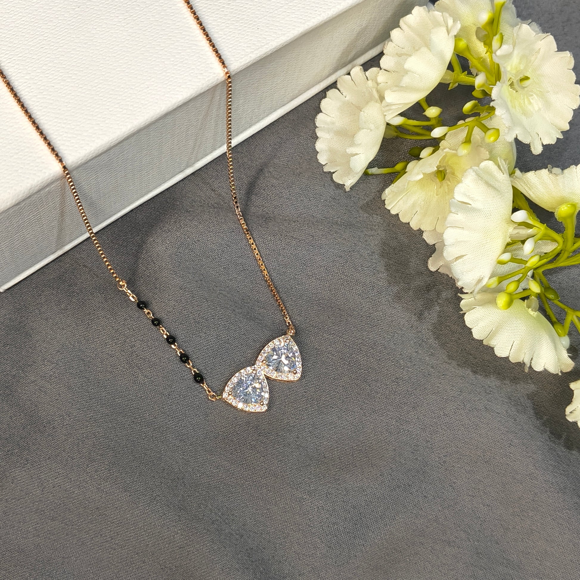 Jewelry with heart-shaped gemstones on a dark surface with white flowers.