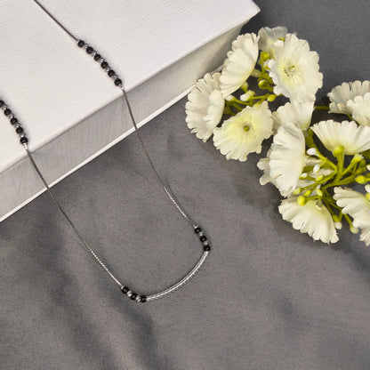 Necklace with black beads on a gray surface with white flowers