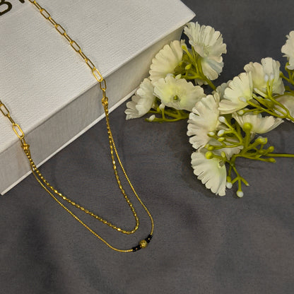 Gold chain necklace on a white box with white flowers on a gray background
