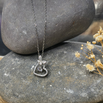 Silver necklace with a heart-shaped pendant on a stone surface
