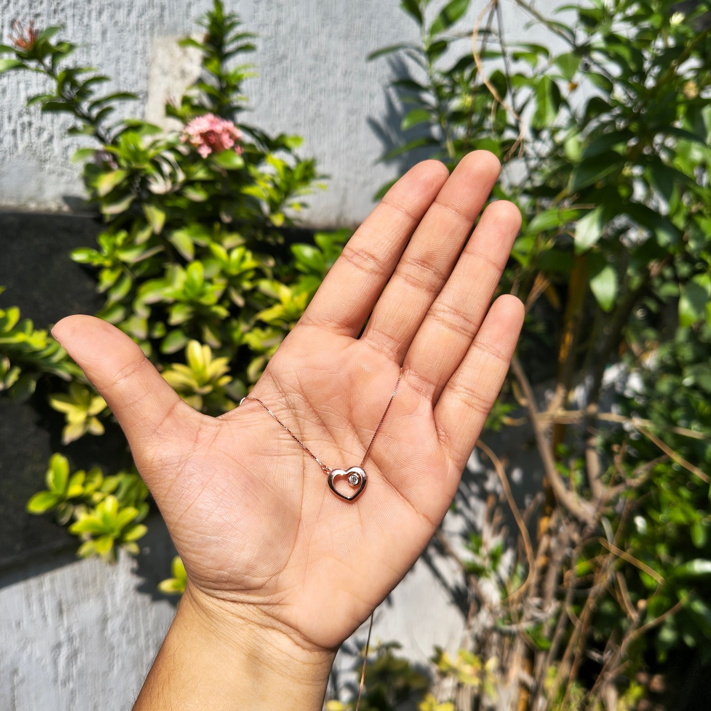 Hand holding a small ring with greenery in the background