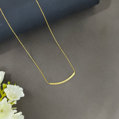 Gold necklace on a dark surface with white flowers