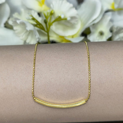 Gold necklace on a person's wrist with a floral background