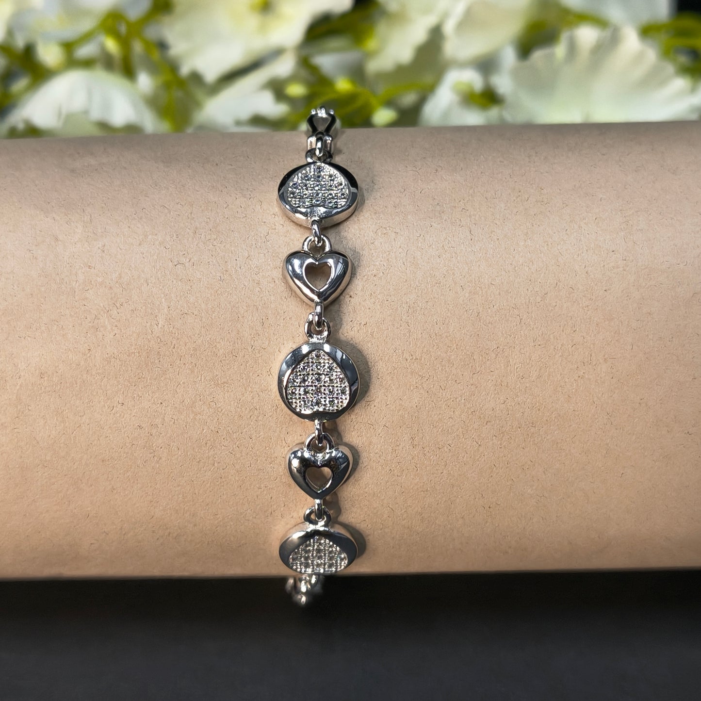 Silver bracelet on a wrist with a blurred floral background