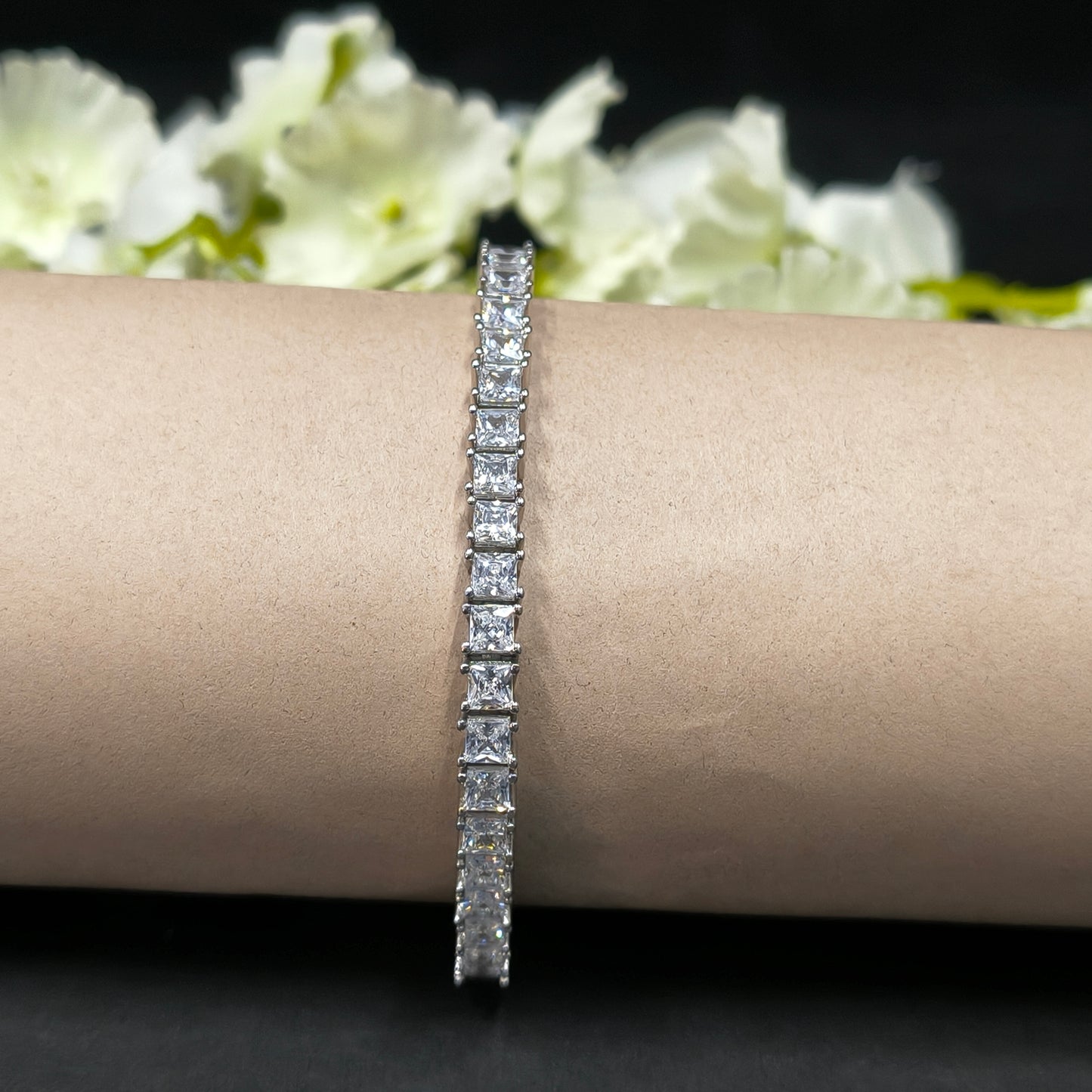 Diamond bracelet on a wrist with a blurred floral background