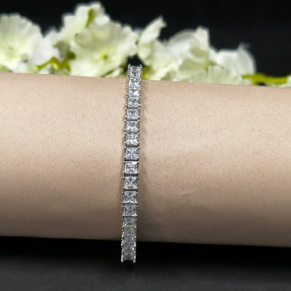 Diamond bracelet on a wrist with a blurred floral background
