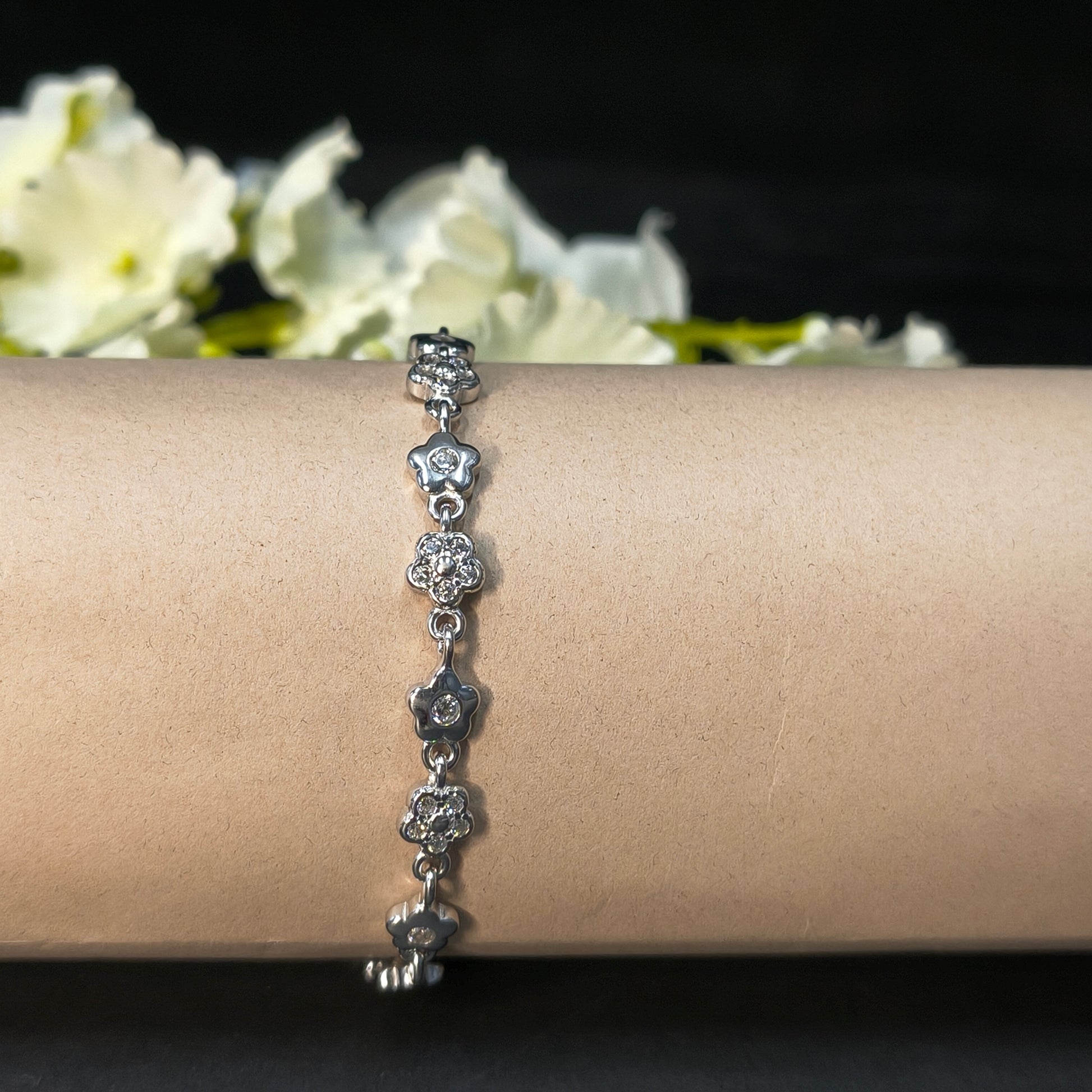 Silver bracelet on a wrist with a blurred floral background