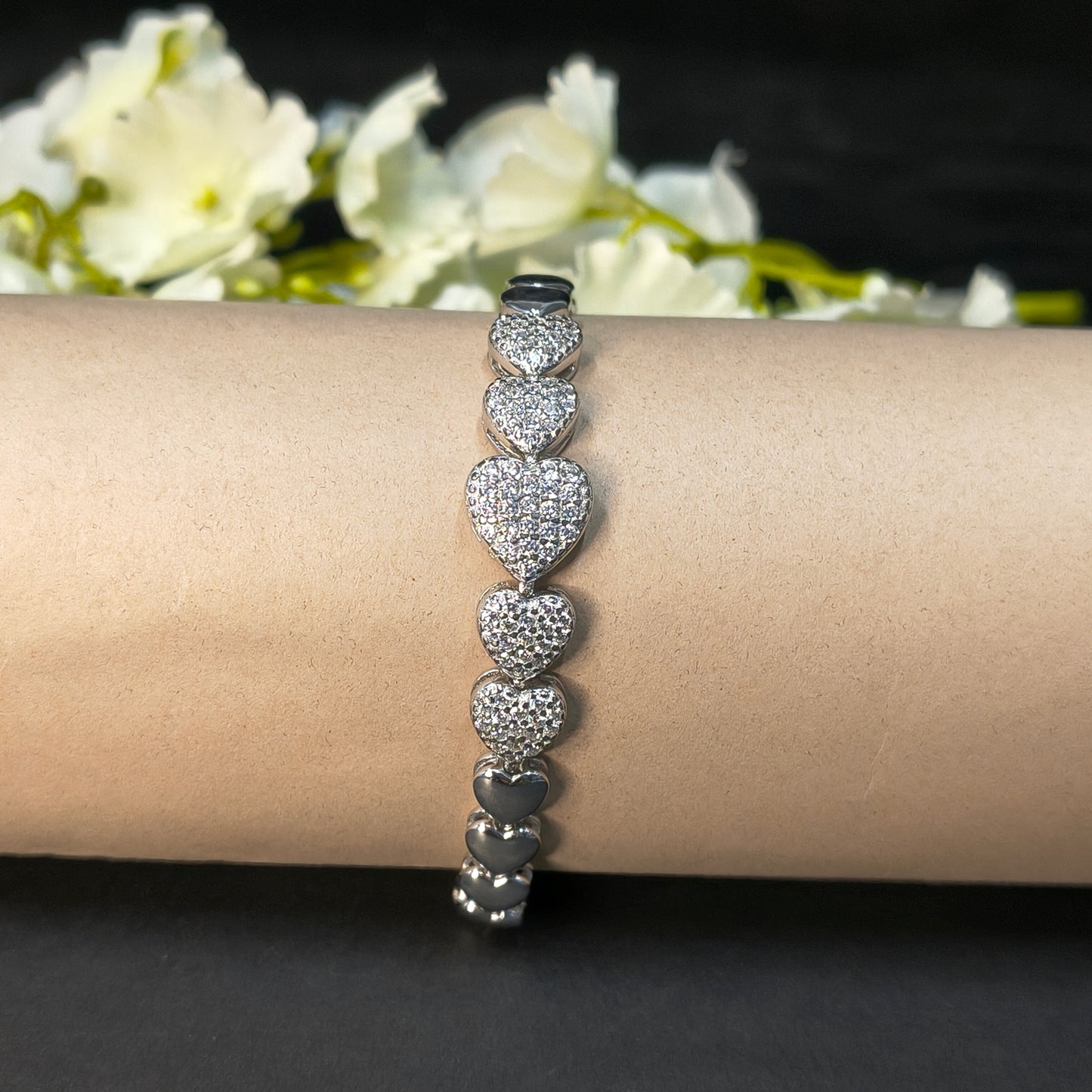 Silver bracelet on a wrist with a blurred floral background