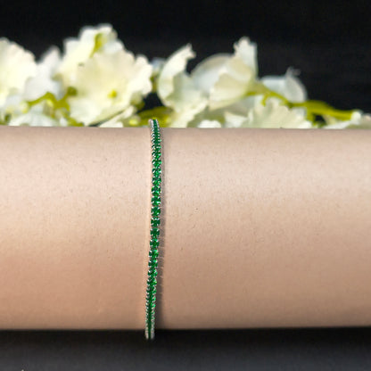 Green bracelet on a wrist with white flowers in the background