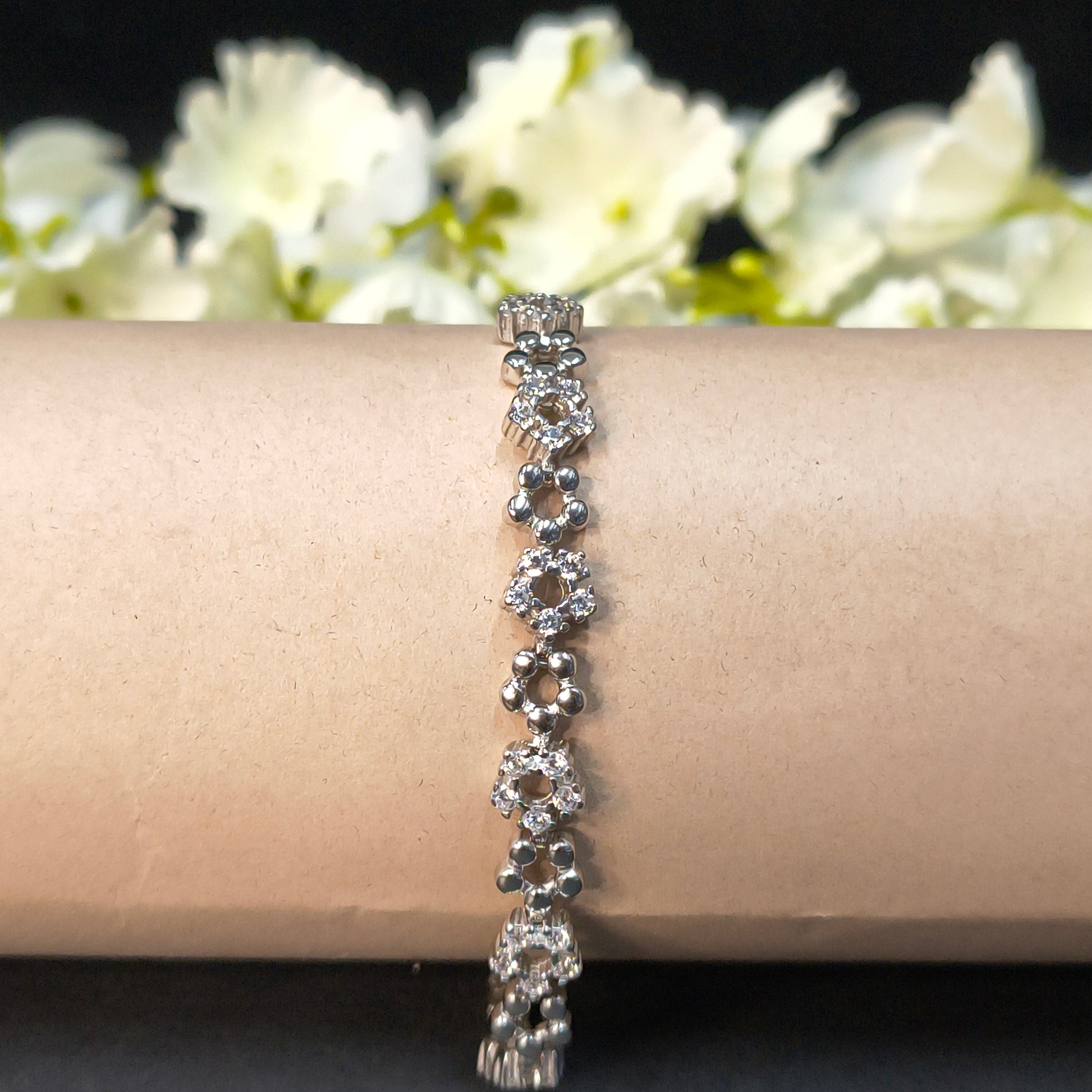 Silver bracelet on a mannequin arm with a floral background