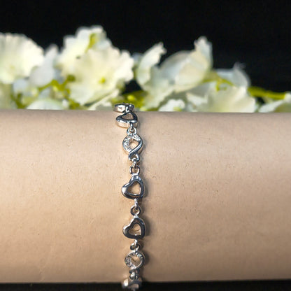 Silver bracelet on a wrist with a blurred background of white flowers