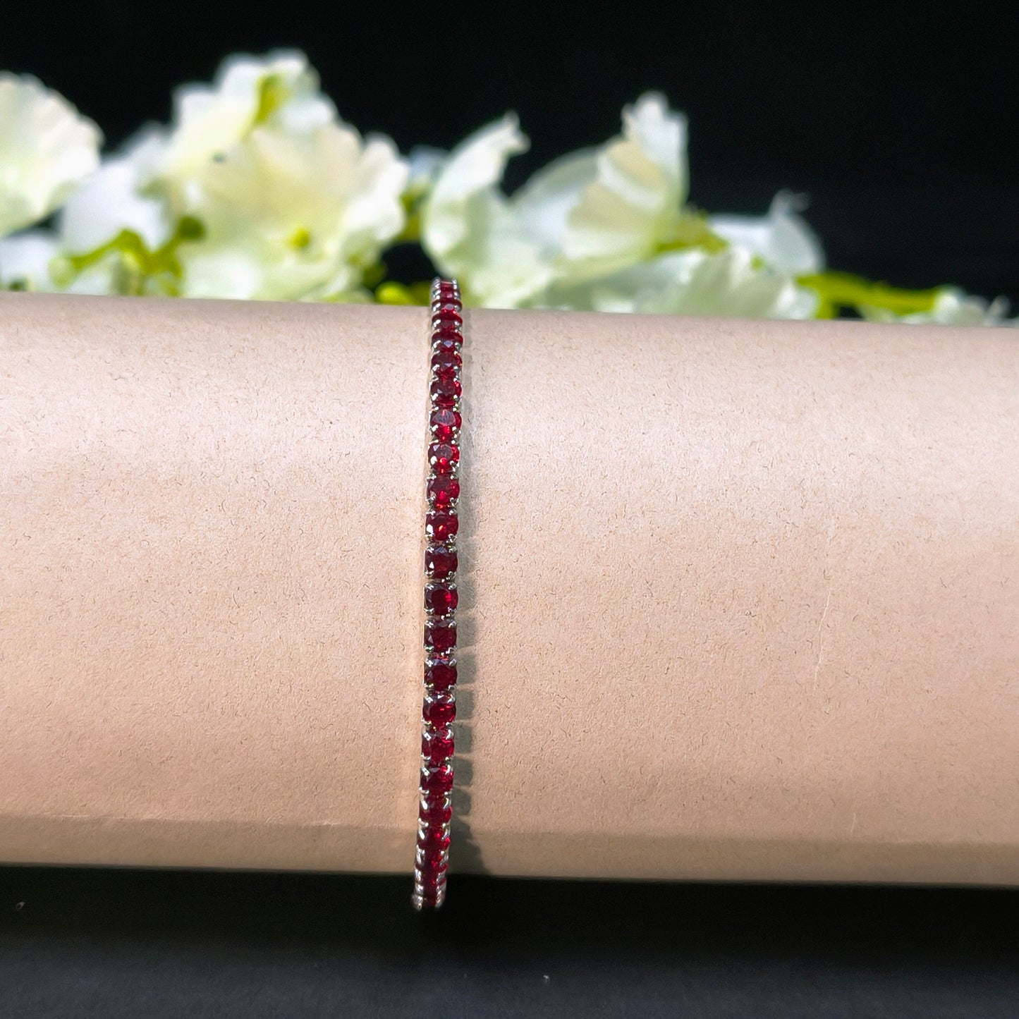 Red beaded bracelet on a wrist with a blurred floral background