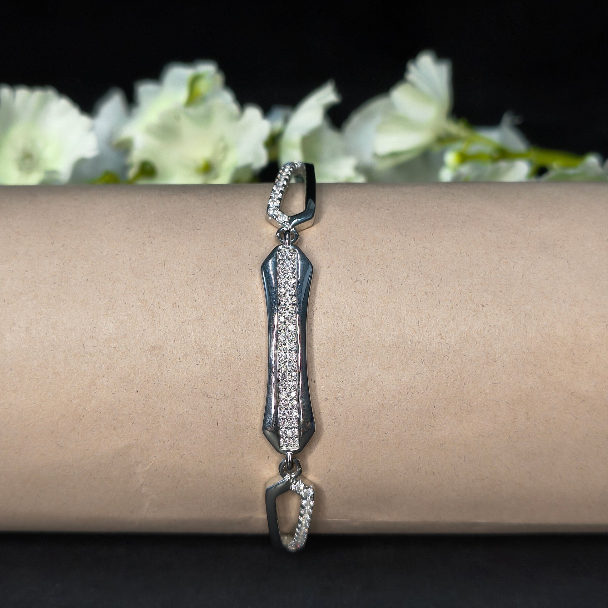 Silver bracelet on a wrist with a blurred floral background