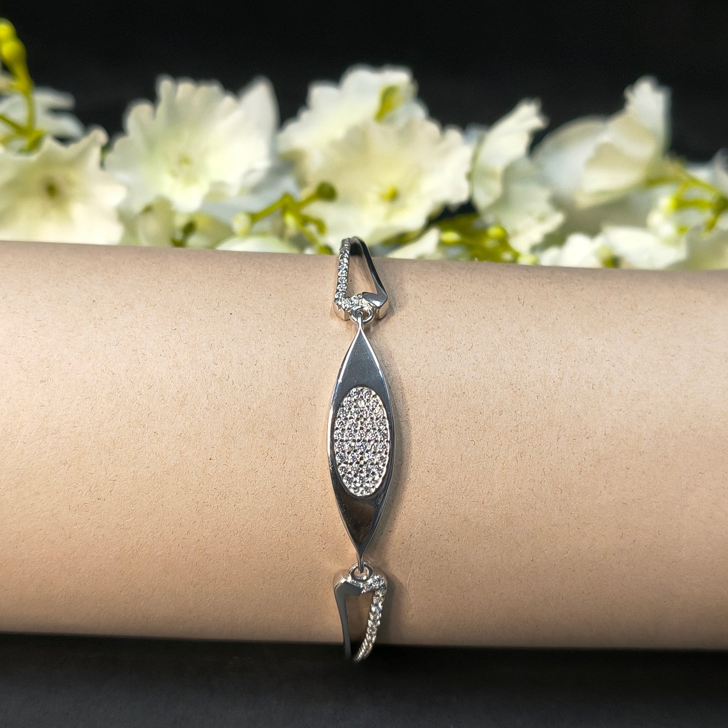 Silver bracelet on a wrist with a blurred floral background