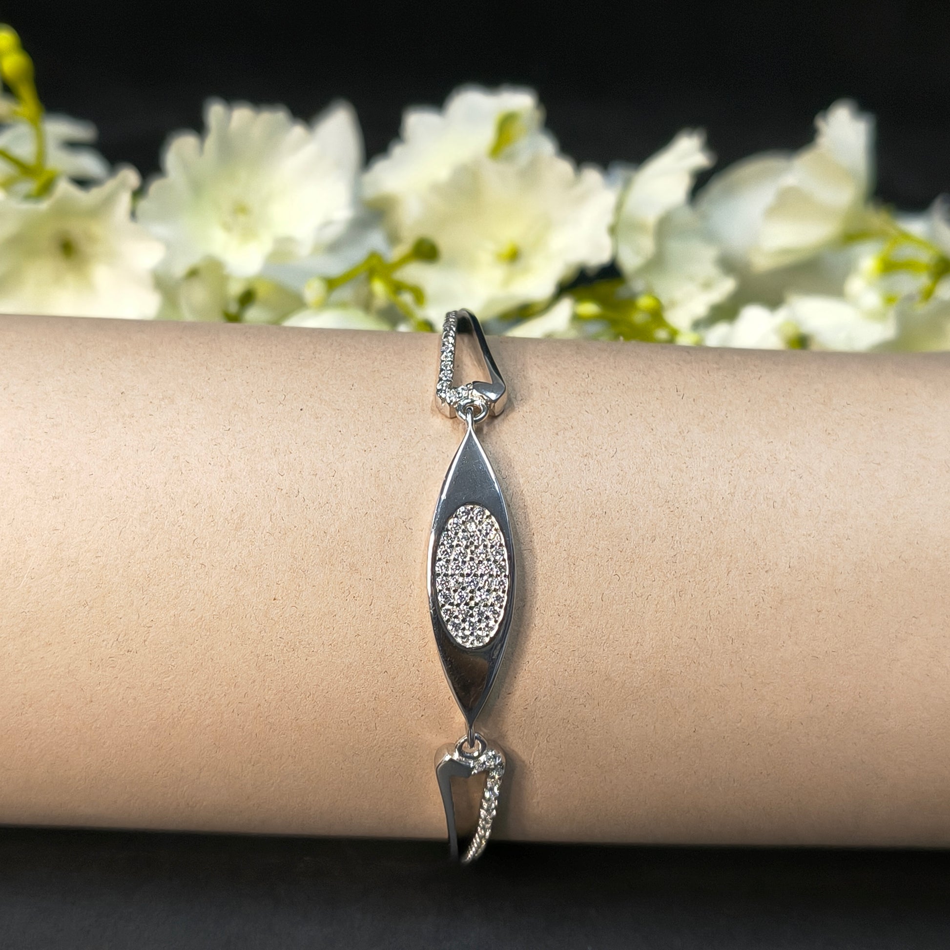 Silver bracelet on a wrist with a blurred floral background
