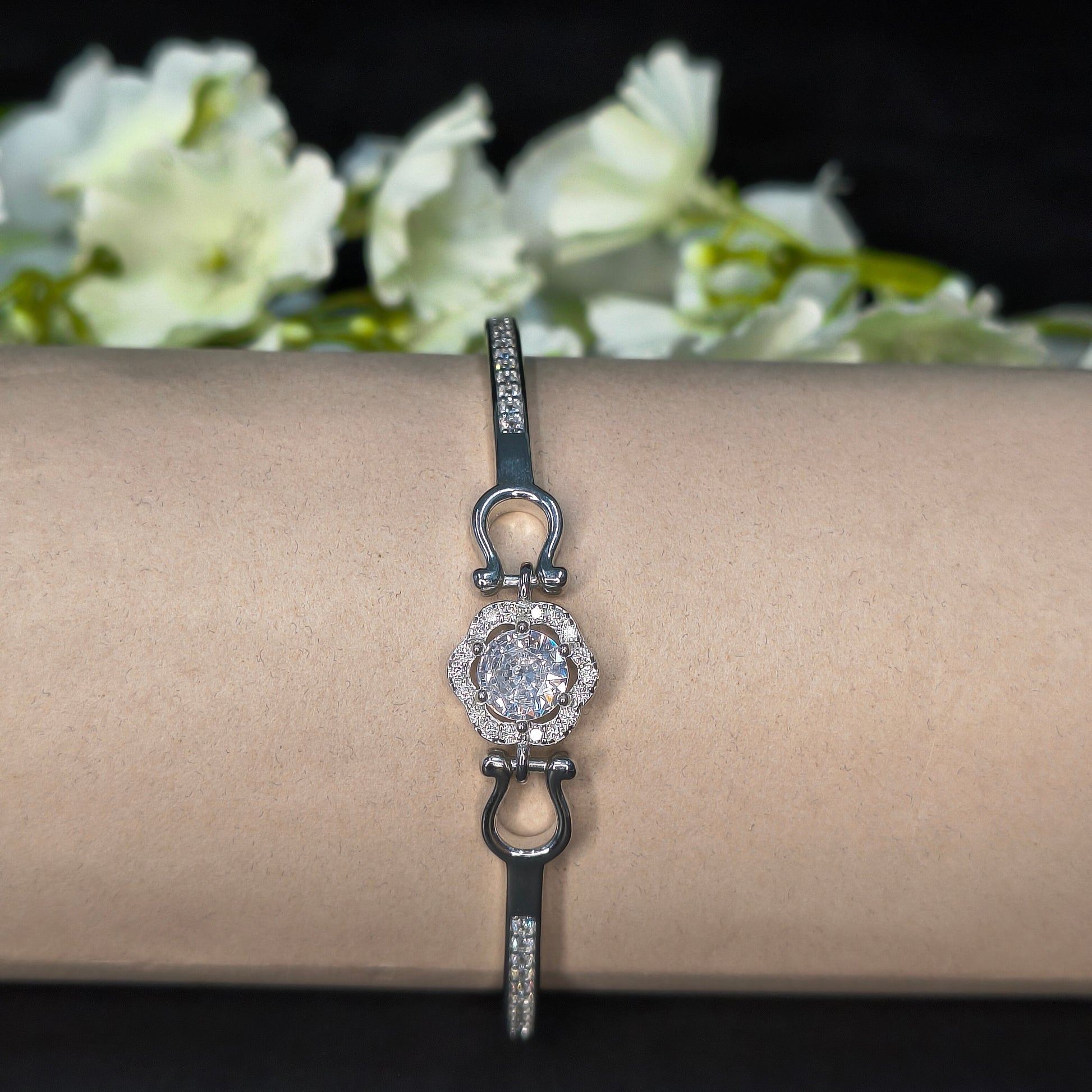 Bracelet with a diamond clasp on a mannequin arm against a floral background