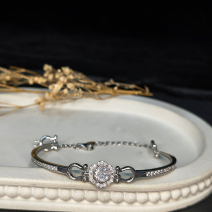 Silver bracelet with a diamond-like stone on a white circular stand with a black background