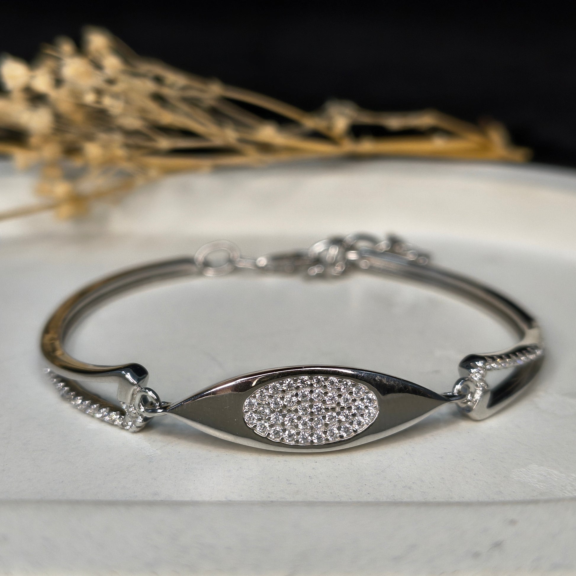 Silver bracelet with eye design on a marble surface