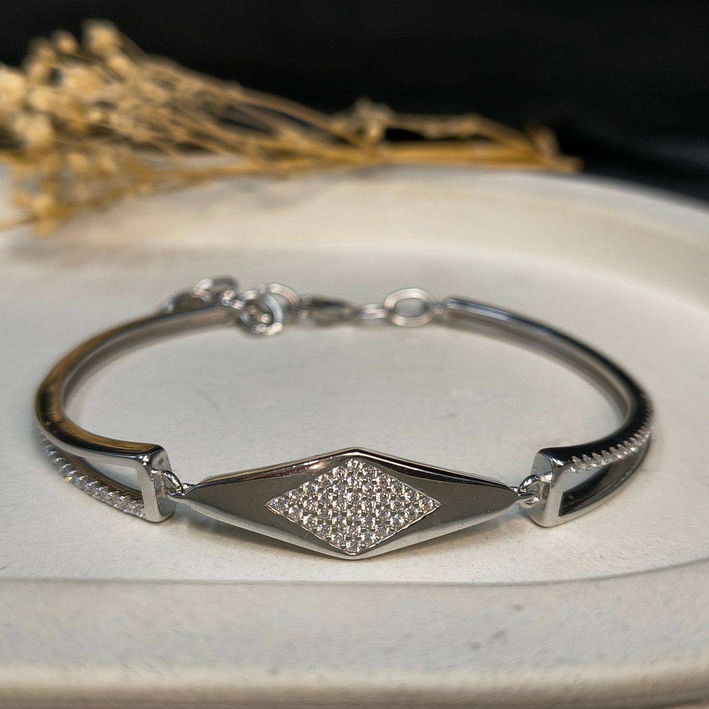 Silver bracelet with a diamond-shaped clasp on a white surface