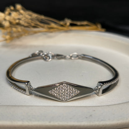Silver bracelet with a diamond-shaped clasp on a white surface