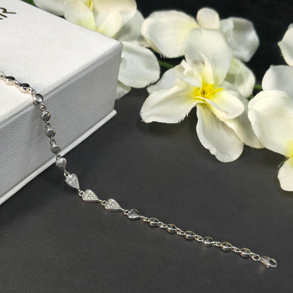 Silver bracelet on a gray surface with white flowers in the background