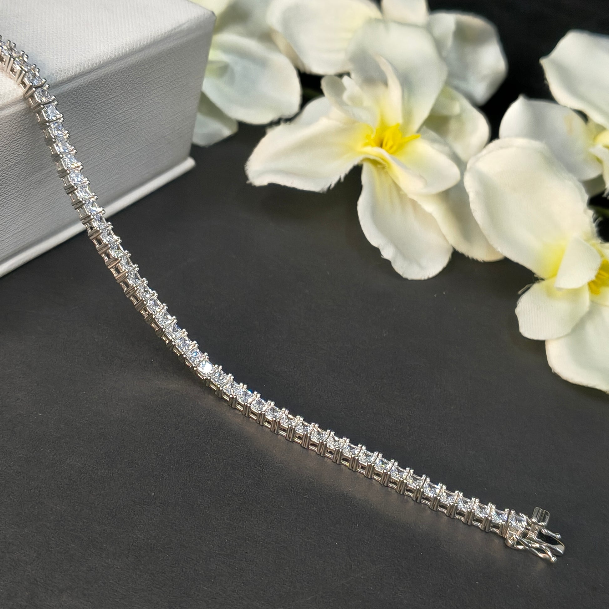 Diamond bracelet on a dark surface with white flowers