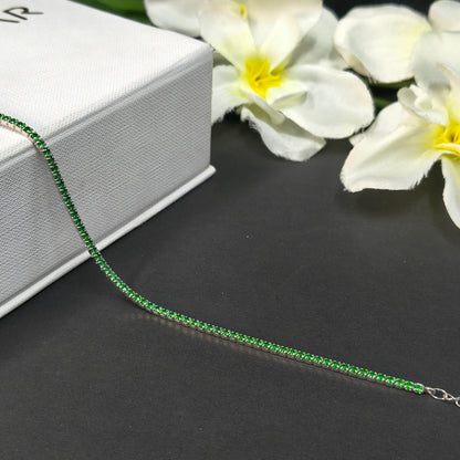 Green beaded necklace on a black surface with white flowers in the background