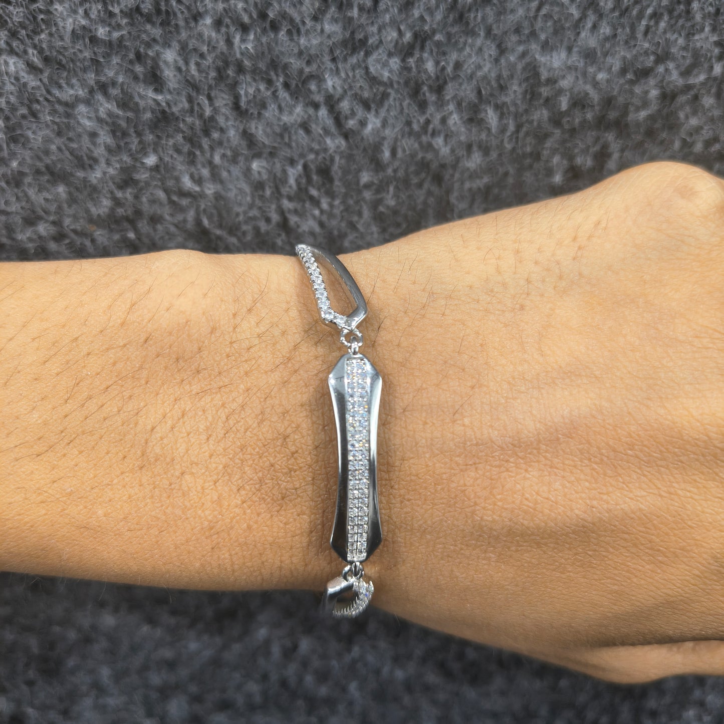 Silver bracelet on a wrist against a dark textured background