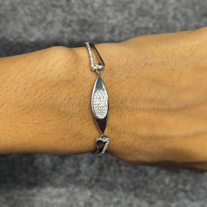 Silver bracelet with a decorative pendant on a wrist against a gray background