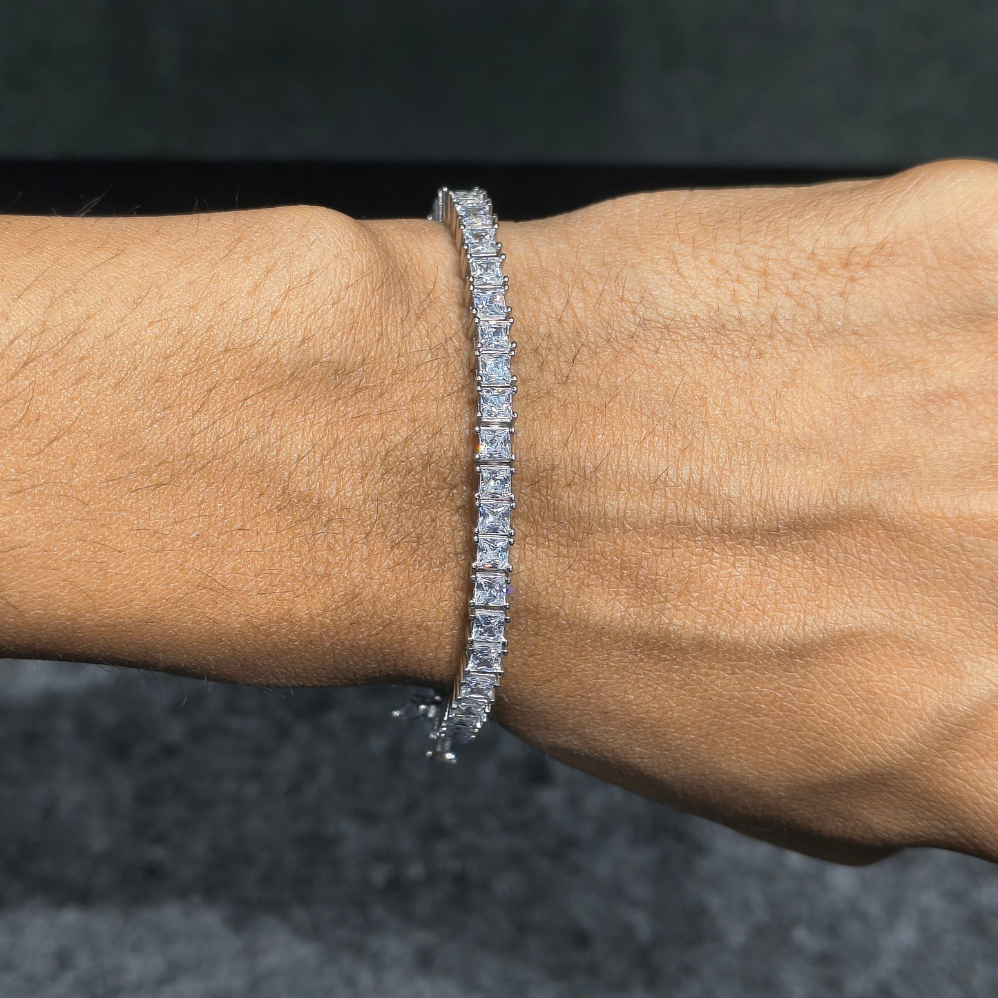 Diamond bracelet on a wrist against a dark background