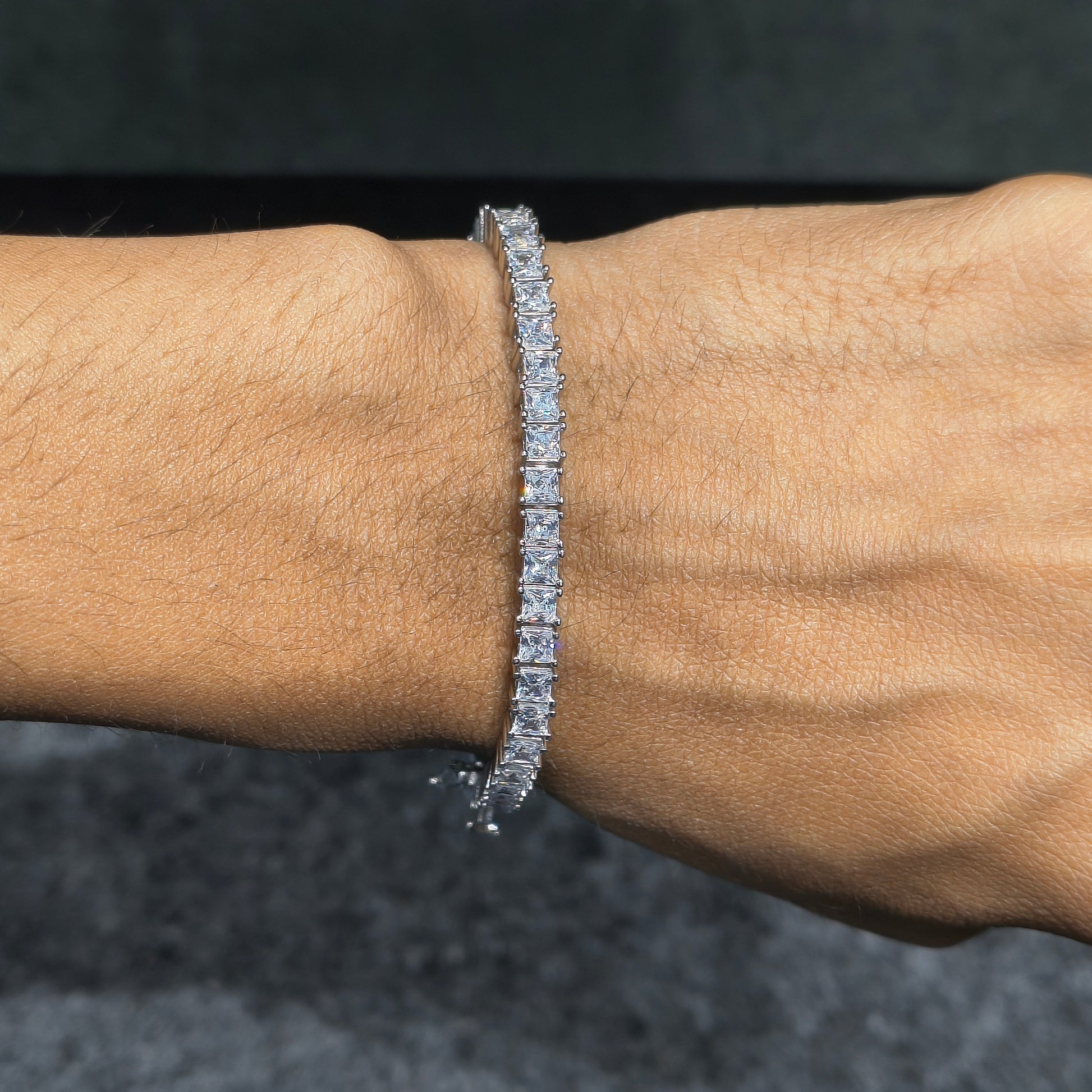 Diamond bracelet on a wrist against a dark background