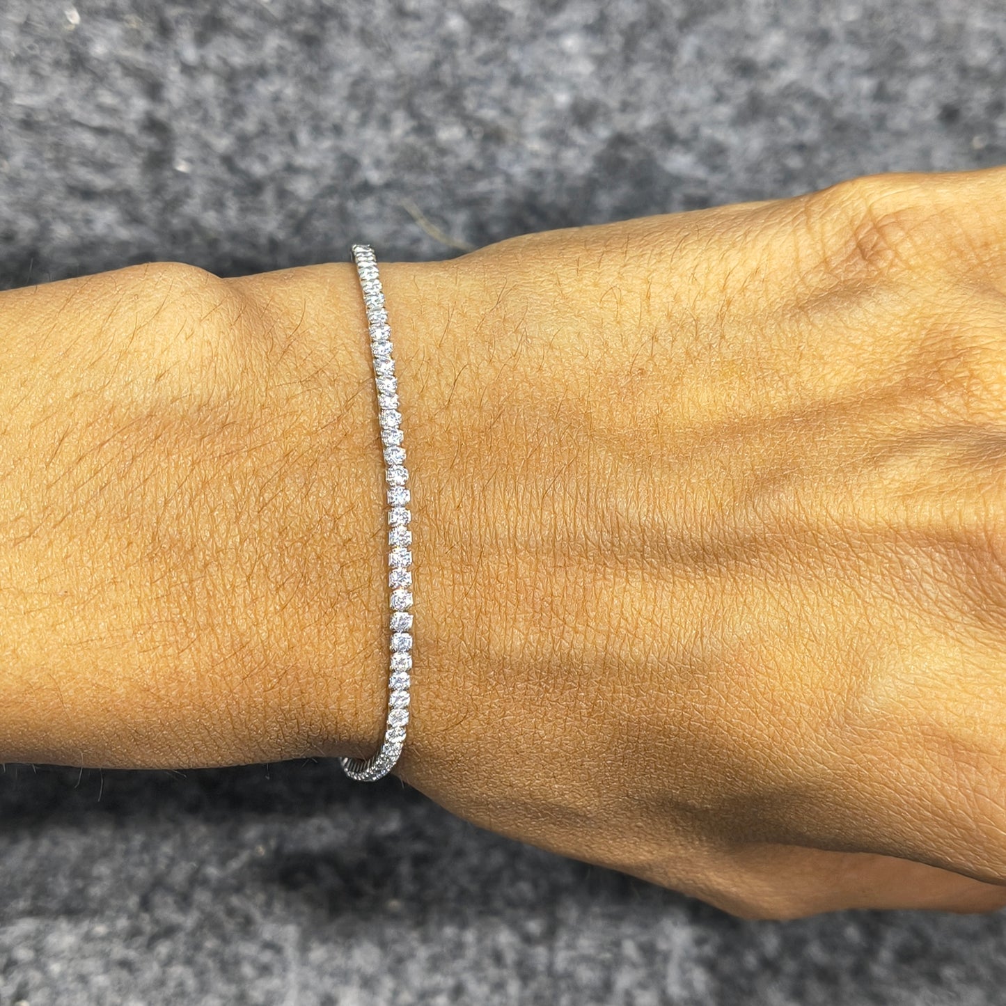 Silver bracelet on a wrist against a gray background