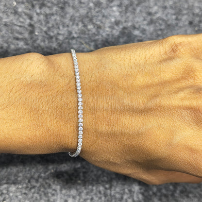 Silver bracelet on a wrist against a gray background