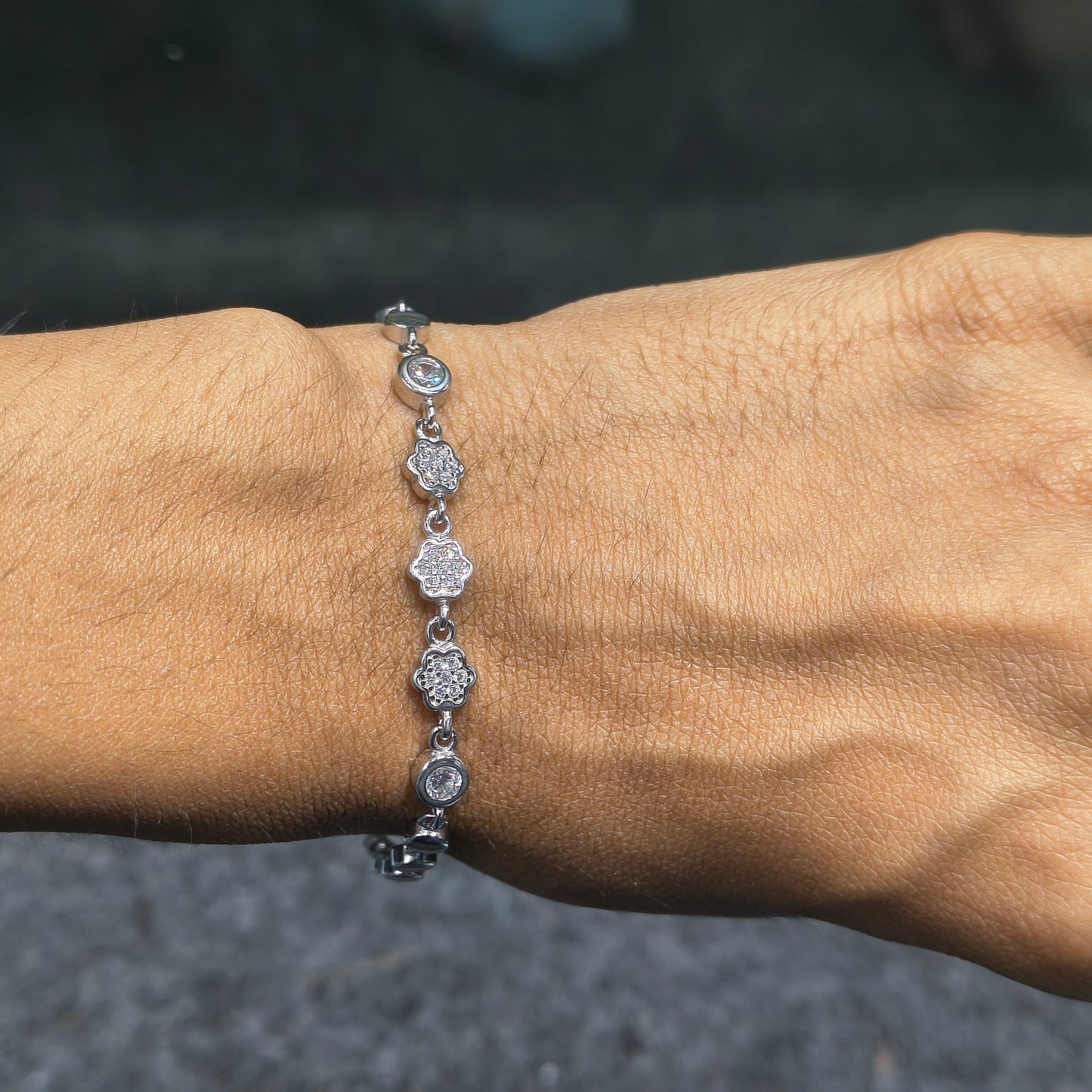 Silver bracelet with circular charms on a wrist against a blurred background