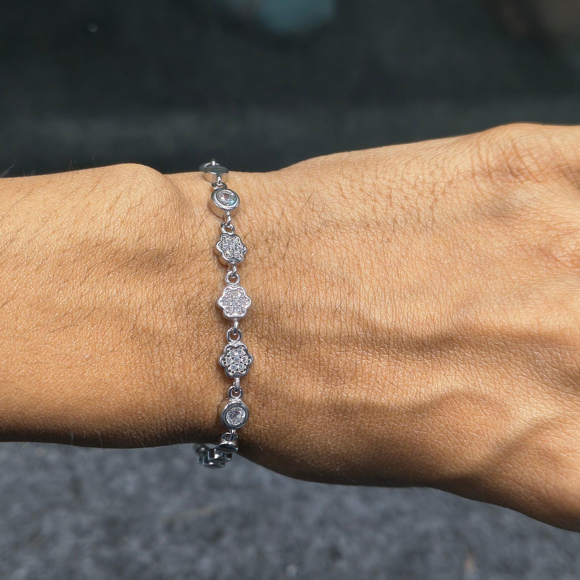 Silver bracelet with circular charms on a wrist against a blurred background