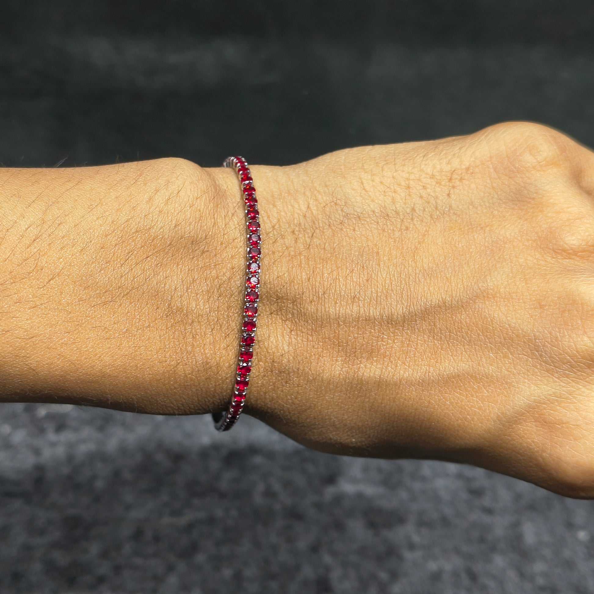 Close-up of a wrist wearing a red beaded bracelet against a dark background