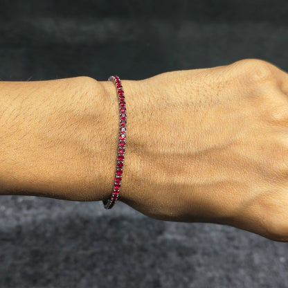Close-up of a wrist wearing a red beaded bracelet against a dark background