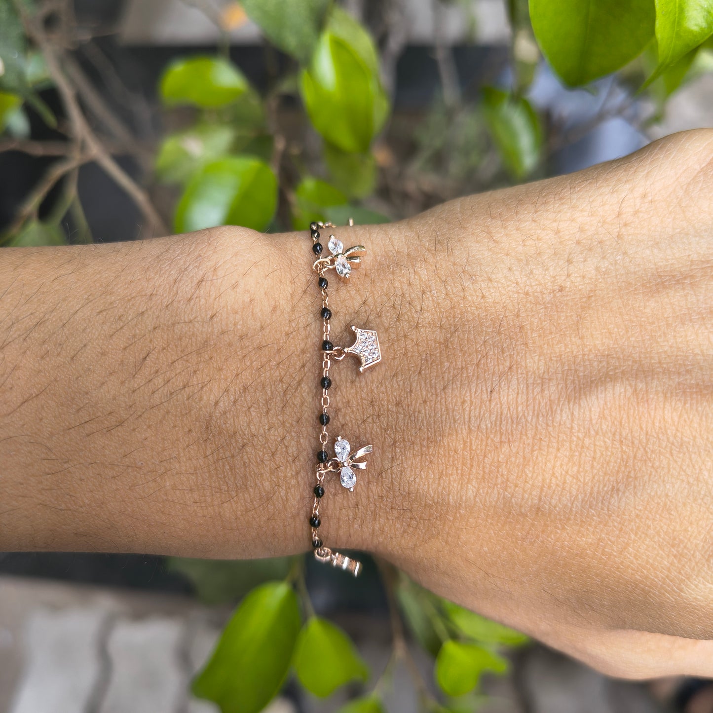 Bracelet with decorative charms on a wrist against a natural background